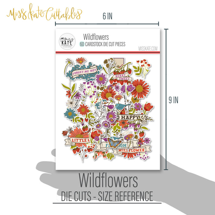 Wildflowers Die Cuts, size guide shown in hand for scale, showing pre-cut scrapbook embellishments for layouts, handmade cards, journals, mini albums, memory pages, and layered paper crafts. Buyer theme: Botanical Die Cuts & Floral Scrapbook Embellishments. Wildflowers Die Cuts with floral titles, daisies, coneflowers, strawberries, berry clusters, birds, butterfly, leaves, stems, bouquets and vintage banner accents