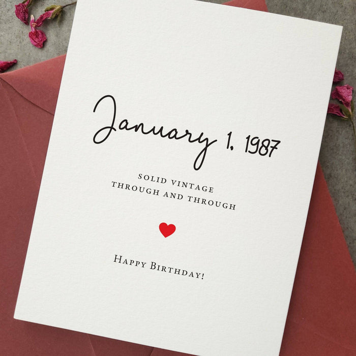 Standing birthday card displayed with burgundy envelope, featuring minimalist typography and custom date front design — XOXOKristen.